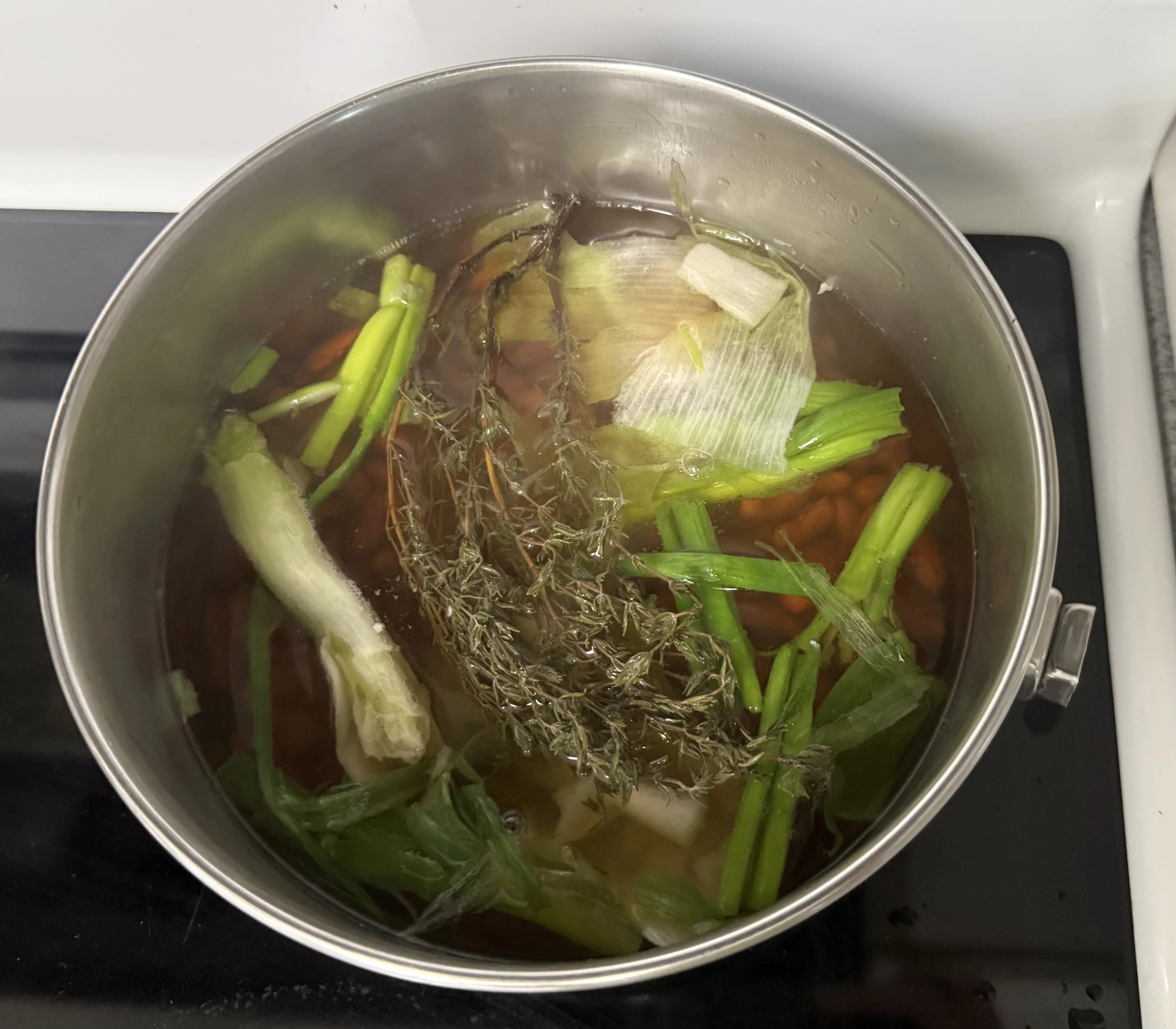 Beans in a pot with water, scallion, thyme and garlic