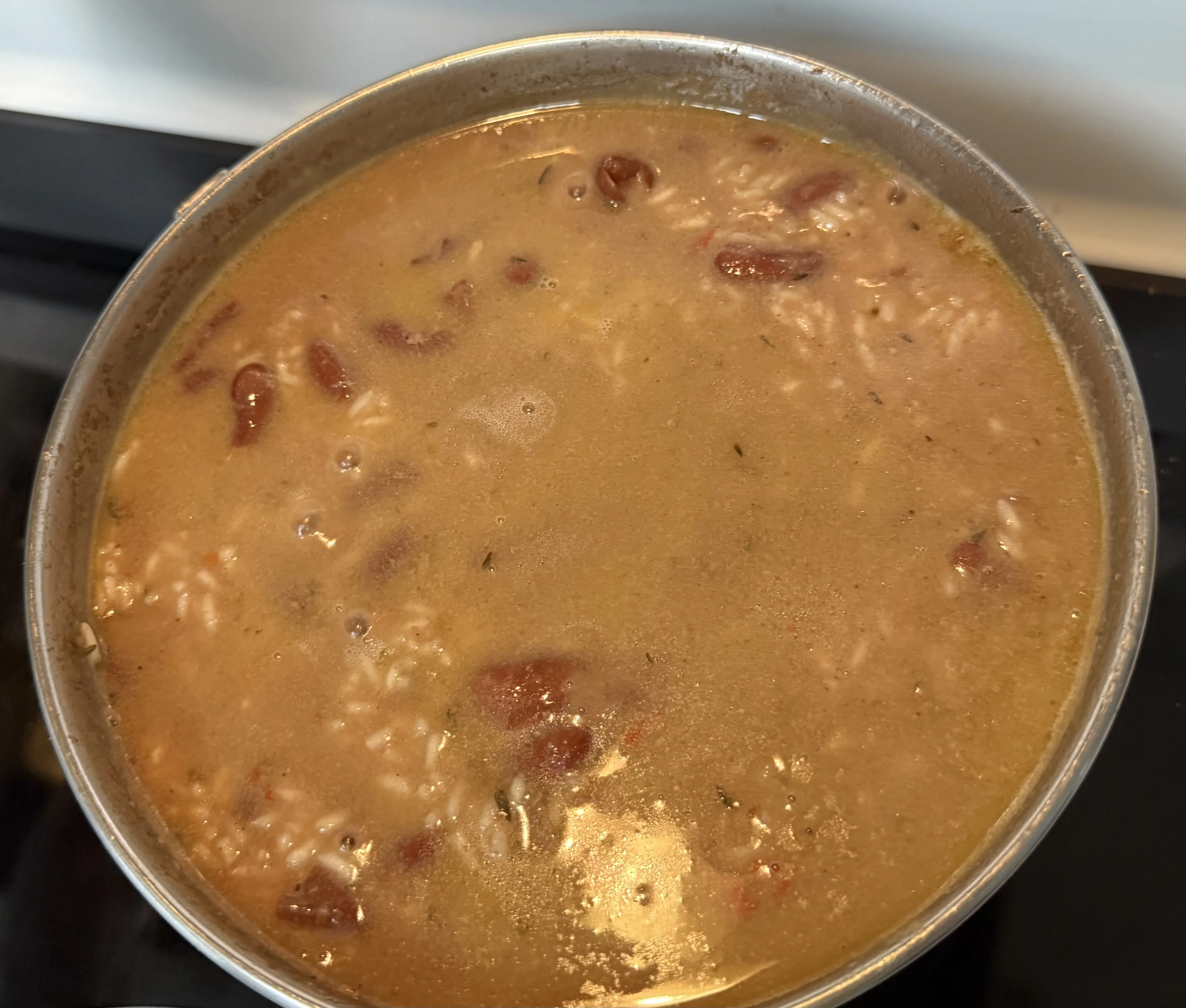 An overhead view of rice and beans in a loose, watery coconut broth